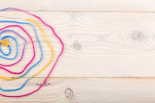 Kolorowe nici i igły na drewnianym tle